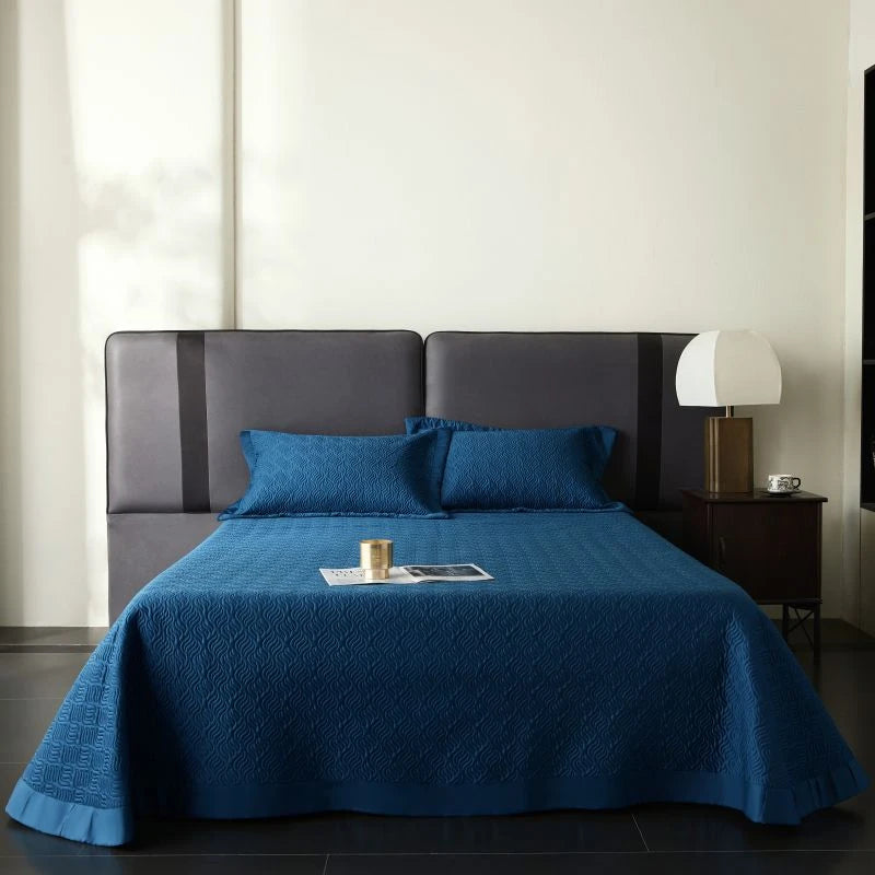 Bed with blue coverlet and pillows in a bedroom setting