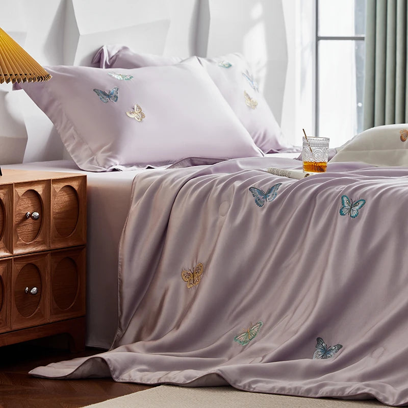 Bed with butterfly-patterned bedding and pillows next to a wooden nightstand.