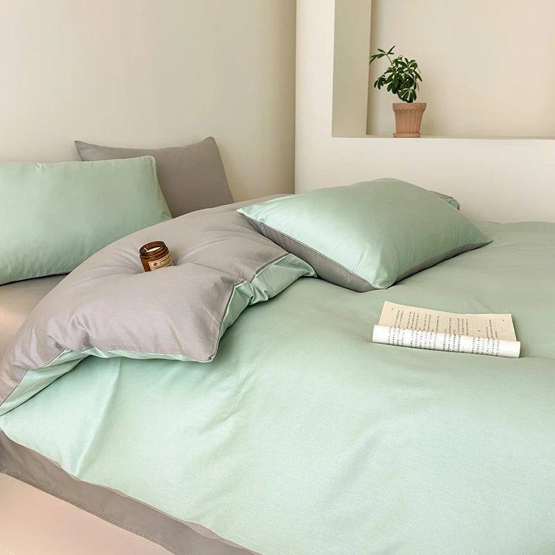 Bed with green and gray bedding in a minimalistic room.