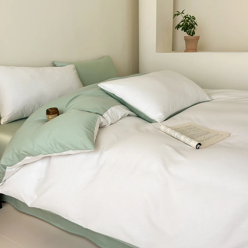 Bed with green and white bedding in a room with a plant on a shelf.
