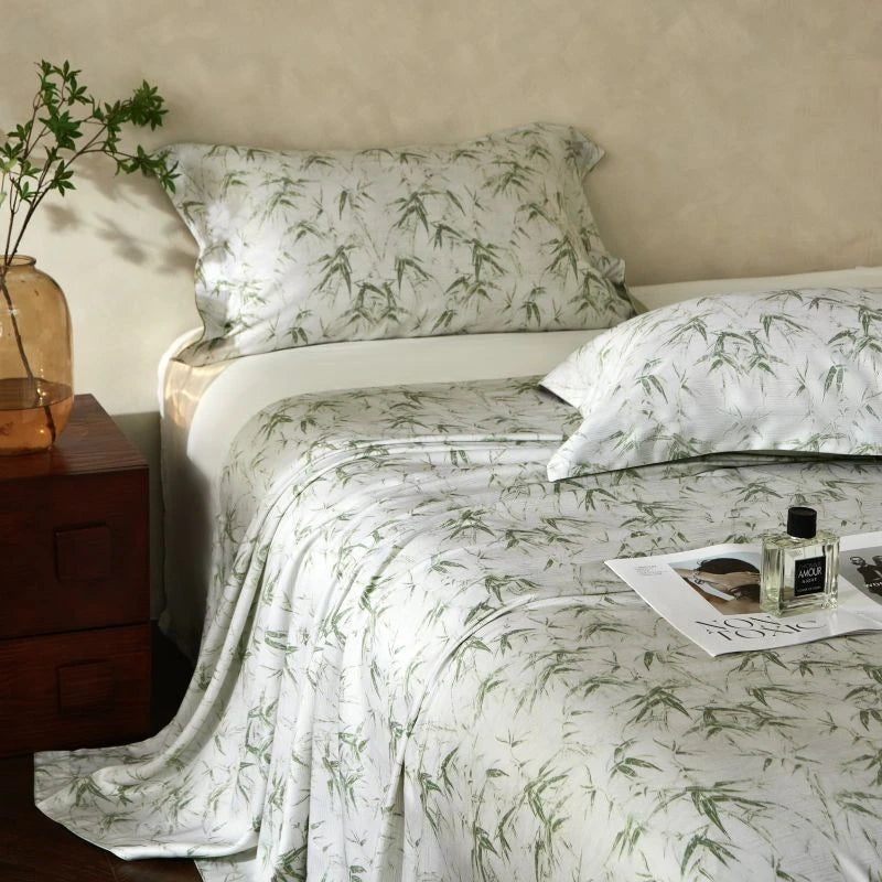 Bed with green and white floral bedding, nightstand with plant, and magazine.