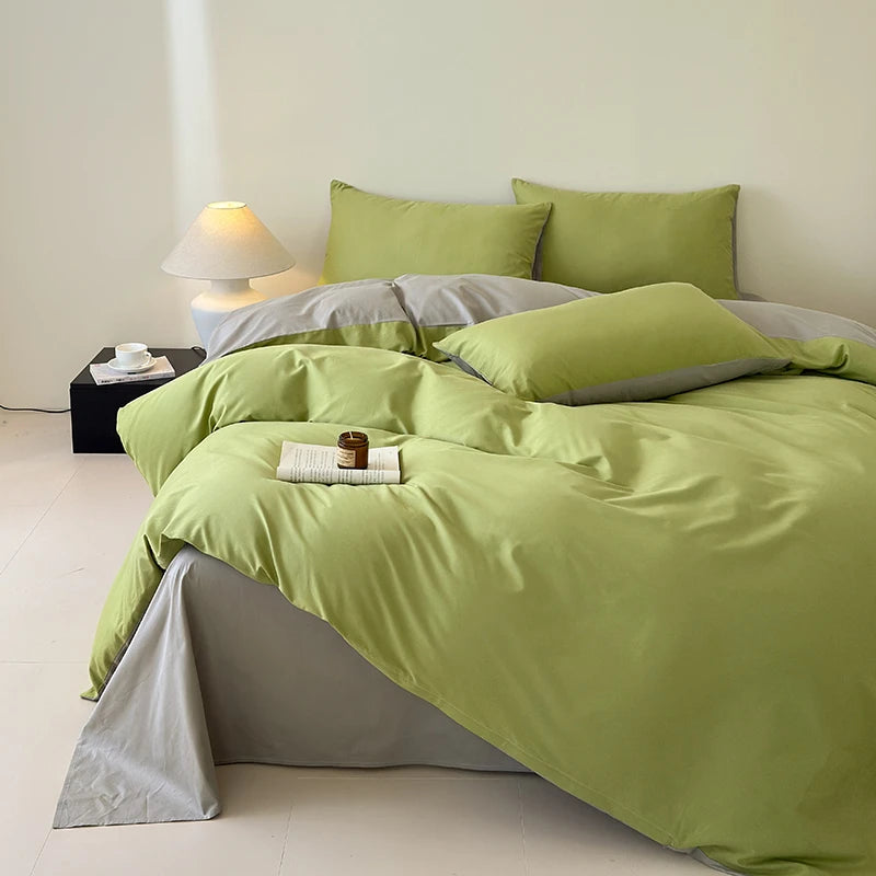 Bed with green bedding and gray pillows in a minimalistic room.