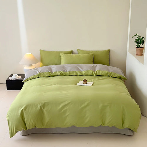 Bed with green bedding and pillows in a minimalistic room.