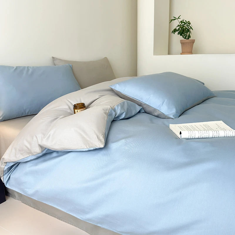 Bed with light blue bedding and pillows in a minimalistic room.