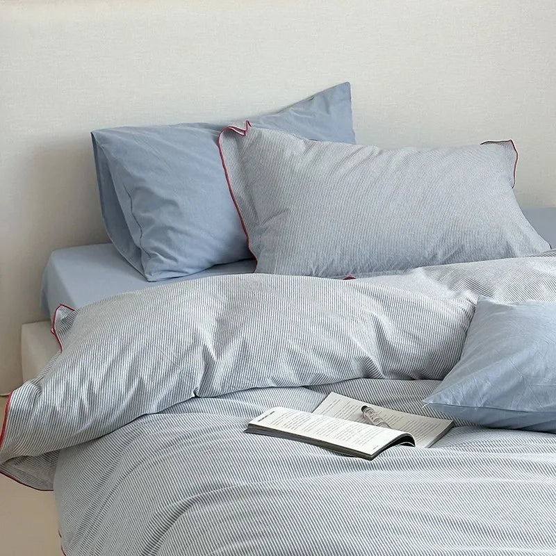 Bed with light blue bedding and pillows on a plain background