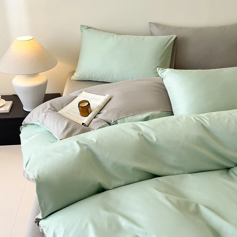 Bed with light green bedding and gray pillows in a bedroom setting.