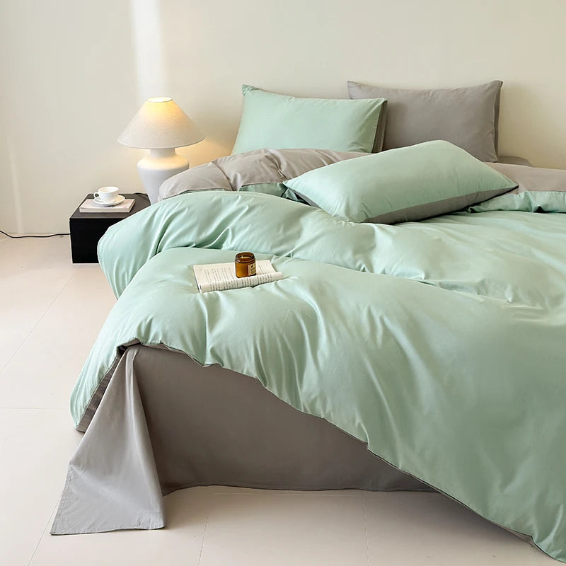 Bed with light green bedding and gray pillows in a minimalistic room.