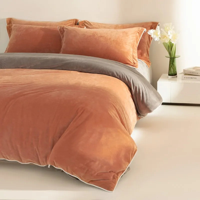Bed with orange velvet bedding and gray blanket in a bedroom setting.