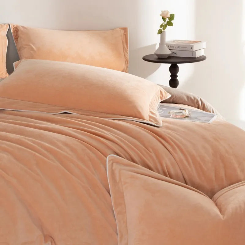 Bed with peach-colored bedding and pillows in a bright room.