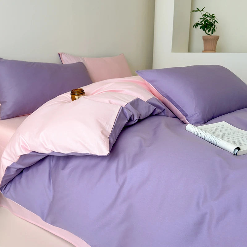 Bed with pink and purple bedding, a plant in the background