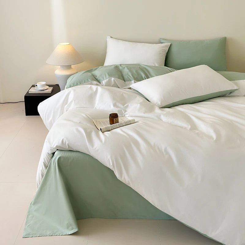 Bed with white and light green bedding in a minimalistic room.