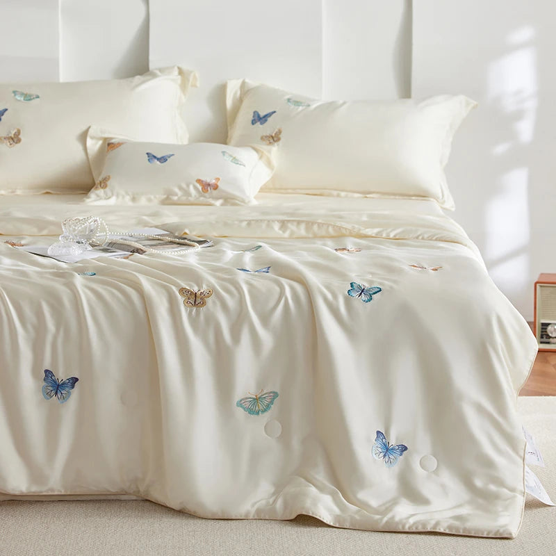 Bed with white bedding featuring embroidered butterflies in a bedroom setting.