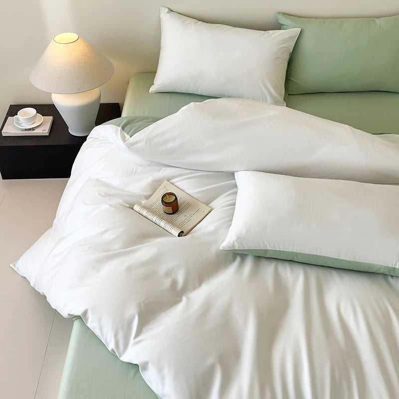 Bed with white comforter and green pillows in a bedroom setting.