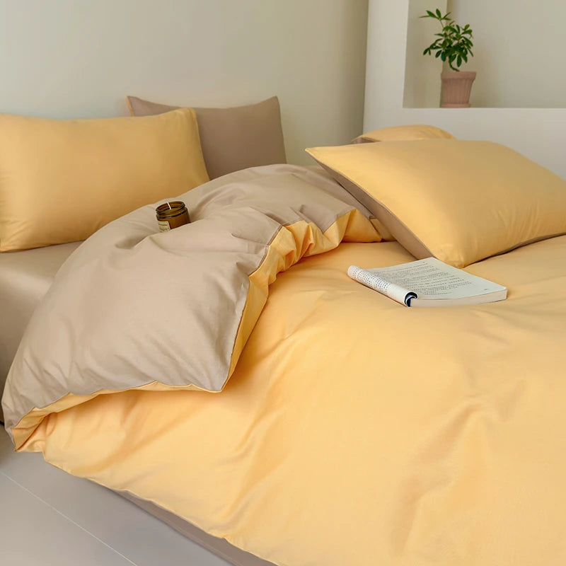 Bed with yellow and beige bedding, pillows, and a plant in the corner.