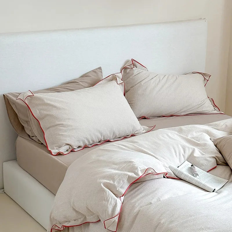 Beige bedding and red trim in a minimalistic room.