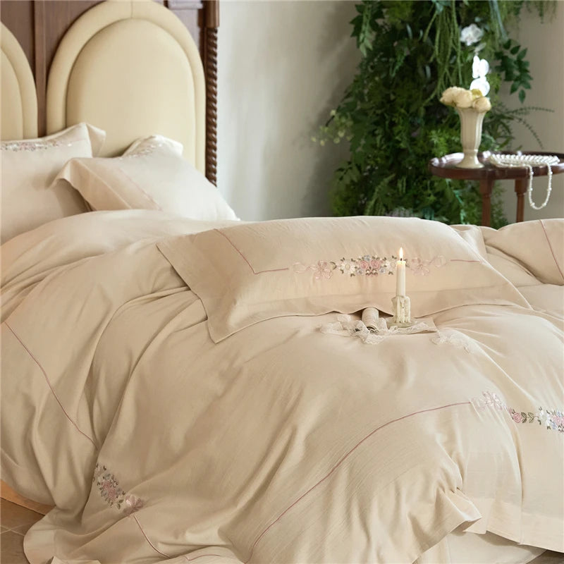 Beige bedspread with floral embroidery on a bed.