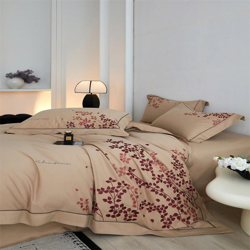 Beige bedspread with red floral patterns on a bed in a bedroom setting.