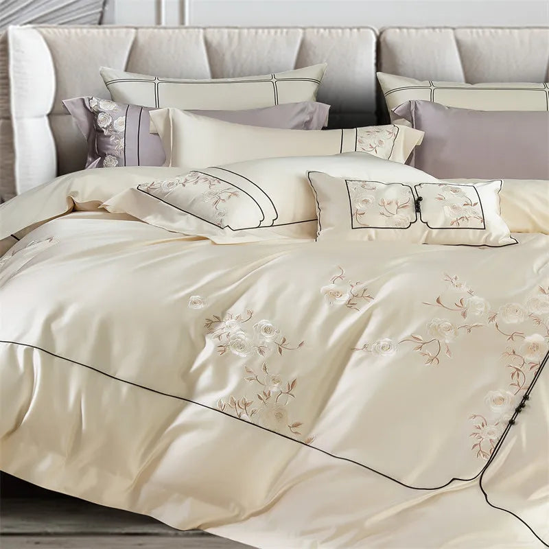 Beige embroidered bedding set on a bed with decorative pillows.