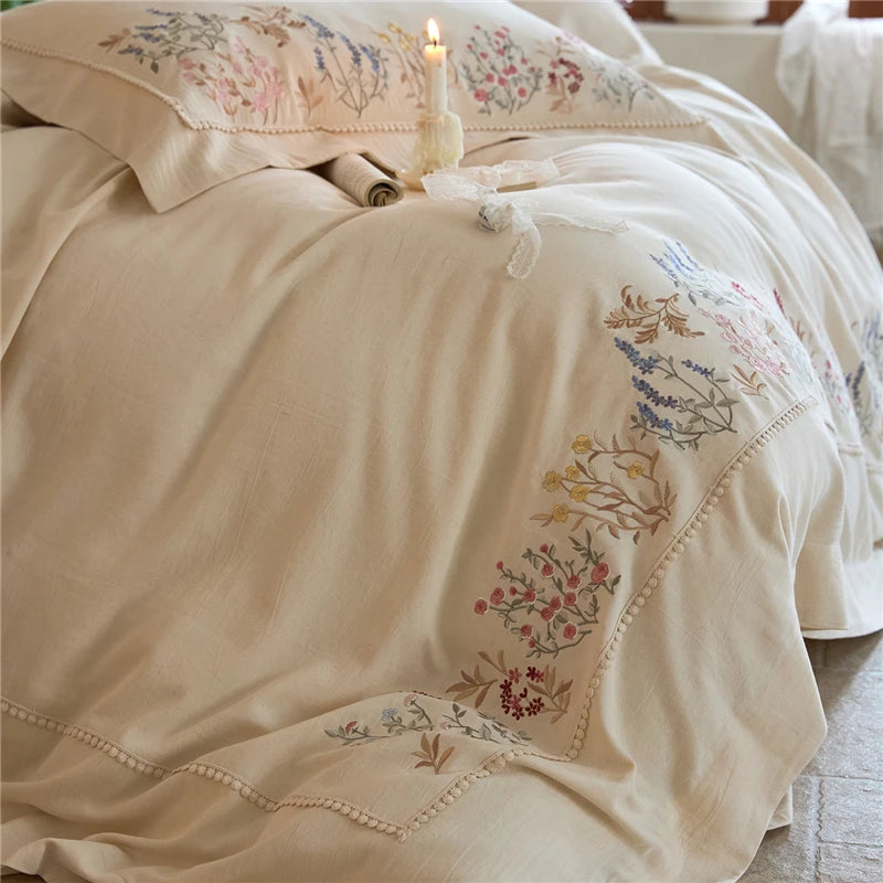 Beige embroidered bedding set on a bed with floral patterns.