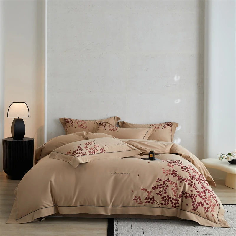 Beige floral bedspread on a bed in a bedroom setting with a lamp and side table.