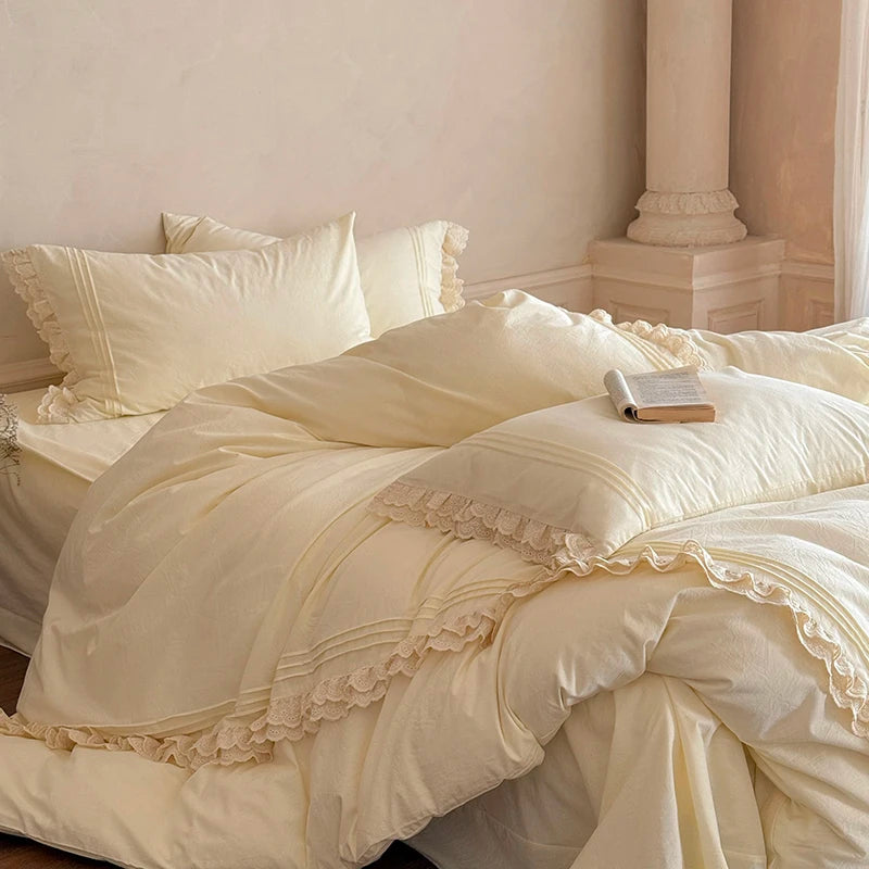Beige ruffled bedding set on a bed in a room with columns.