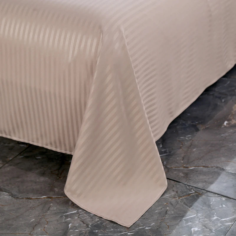 Beige textured bedspread on a bed against a dark marble floor.