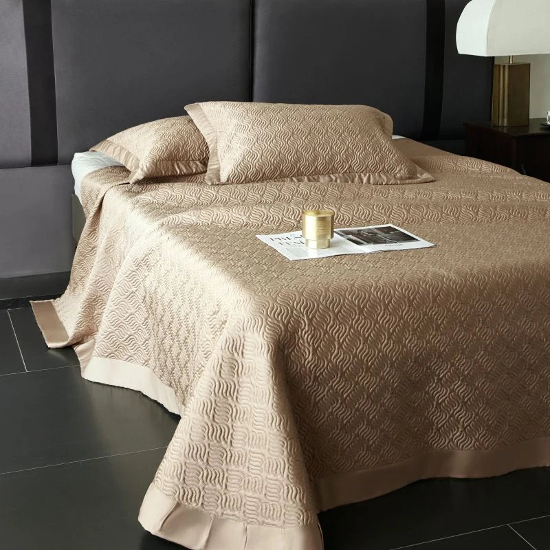 Beige textured bedspread on a bed with pillows.