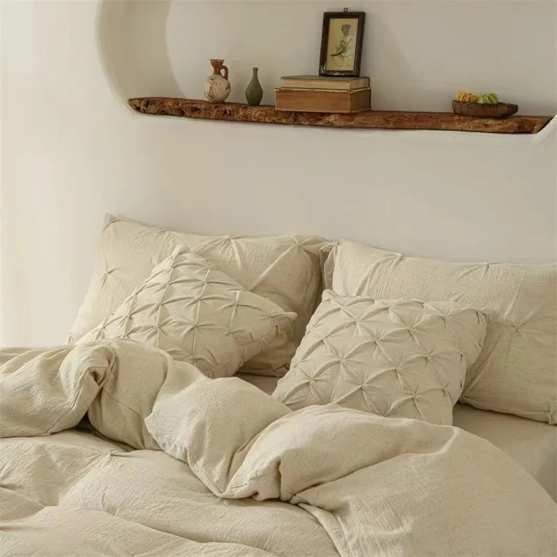 Beige textured pillows and duvet on a a bed with a wooden shelf in the background