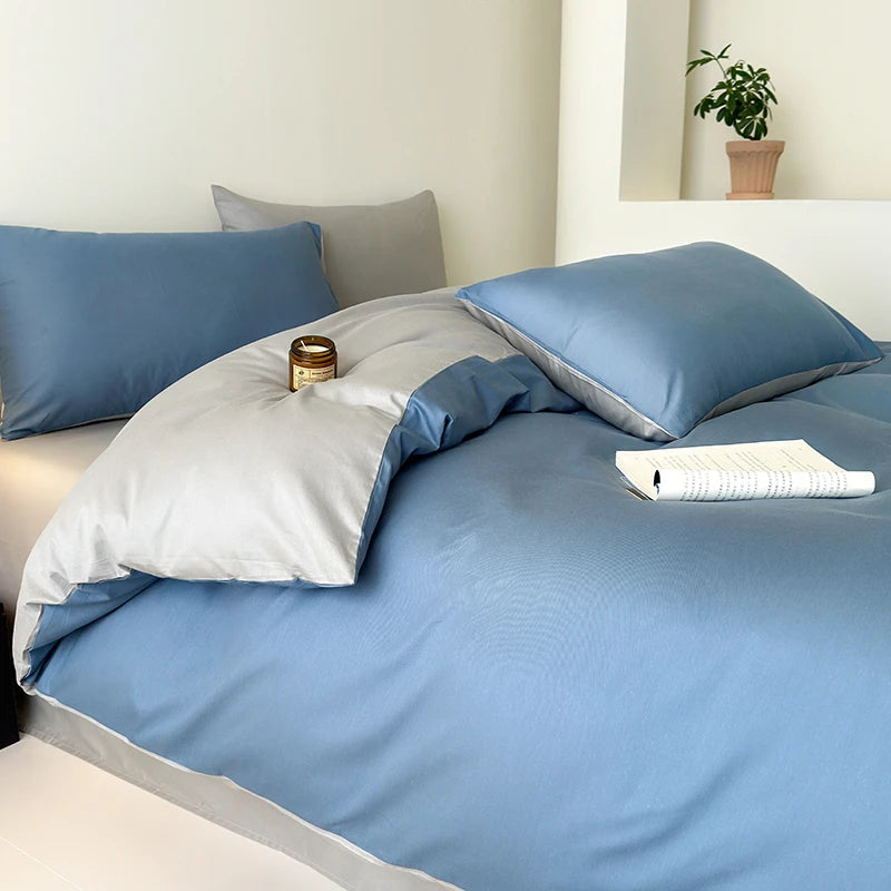 Blue and gray bedding set on a bed with a plant in the background