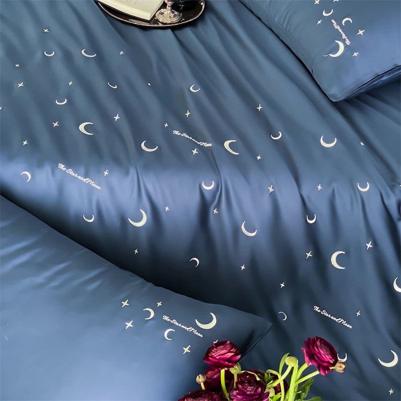 Blue bedding set with moon and star pattern, featuring pillows and a vase of flowers.