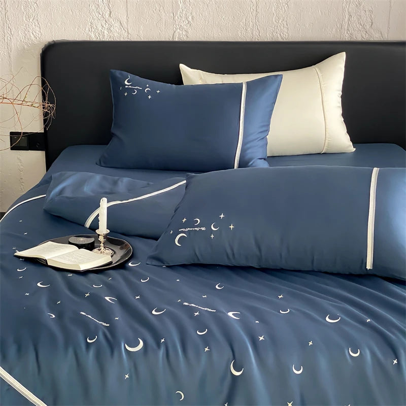 Blue bedding set with moon and star patterns on a bed with white walls.