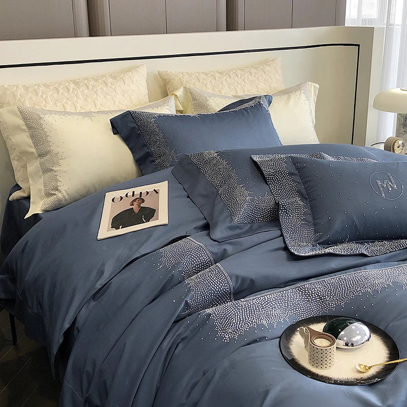Blue bedspread with decorative pillows on a bed in a bedroom setting.