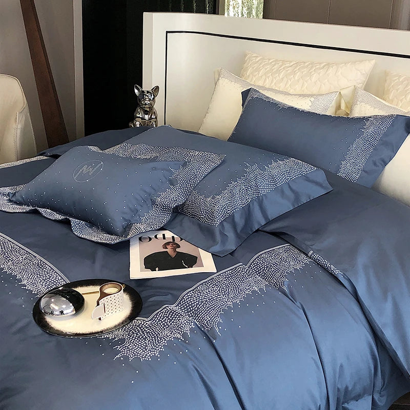 Blue bedspread with lace details on a bed in a bedroom setting.