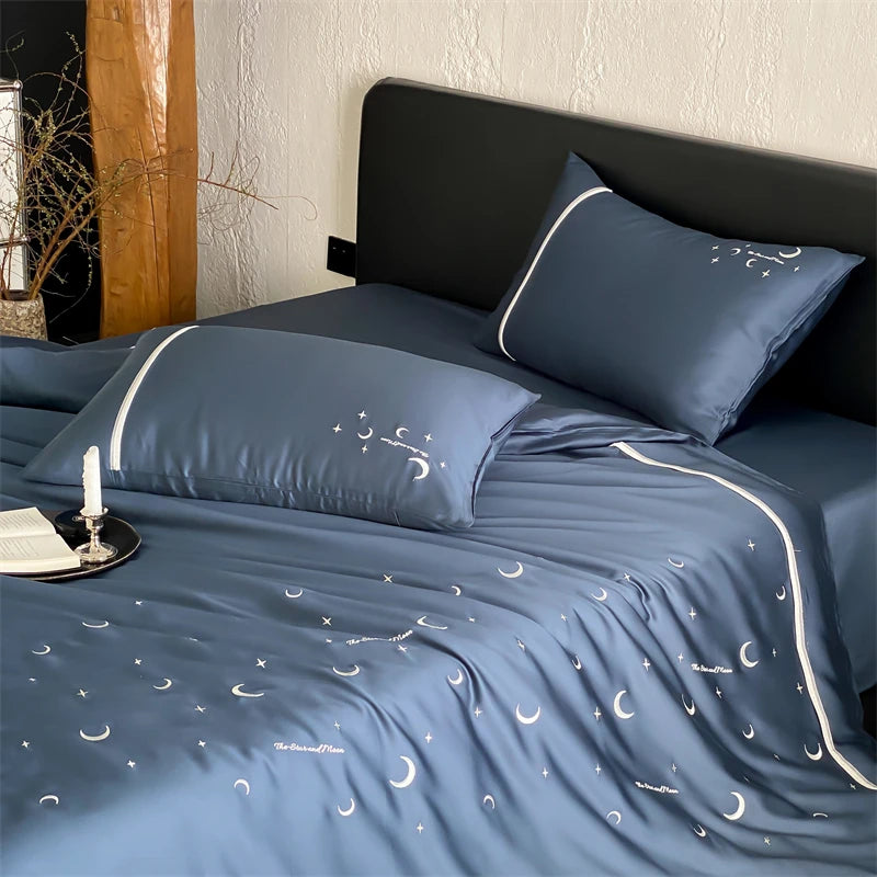 Blue bedspread with moon and star pattern on a bed in a bedroom setting.