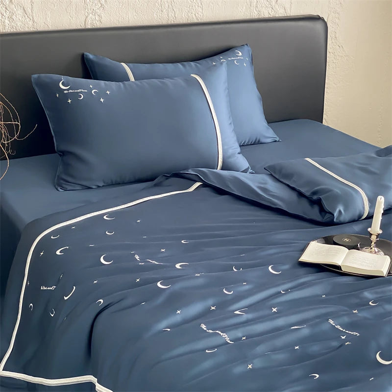 Blue bedspread with moon and star patterns on a bed with matching pillows.