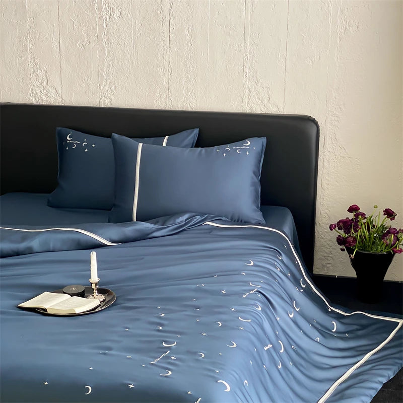 Blue bedspread with moon patterns on a bed in a bedroom setting.