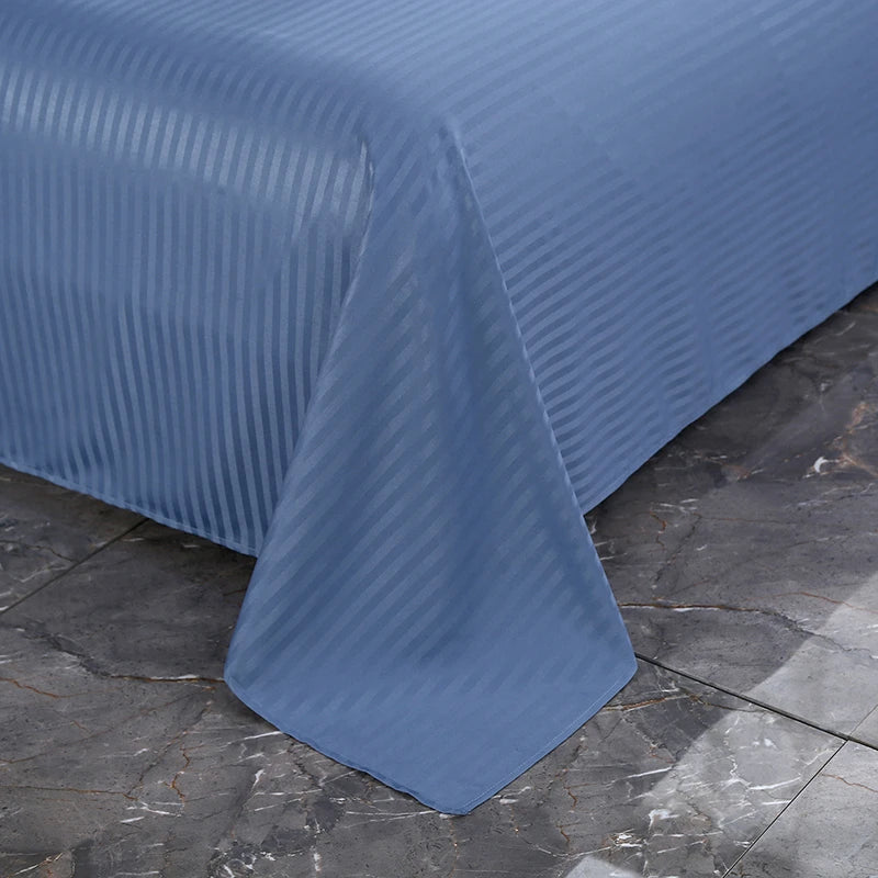 Blue striped bedspread on a bed with a dark stone floor background
