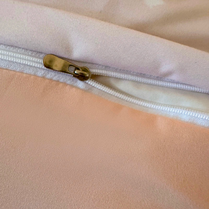 Close-up of a beige fabric with a white zipper and gold zipper pull.