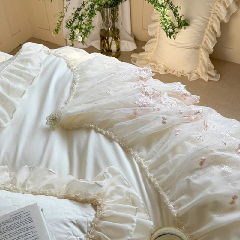 Close-up of a white lace dress with floral details on a bed.