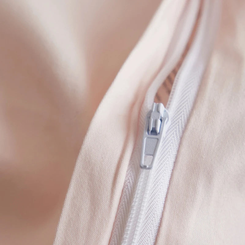 Close-up of a zipper on a light pink garment with a blurred background