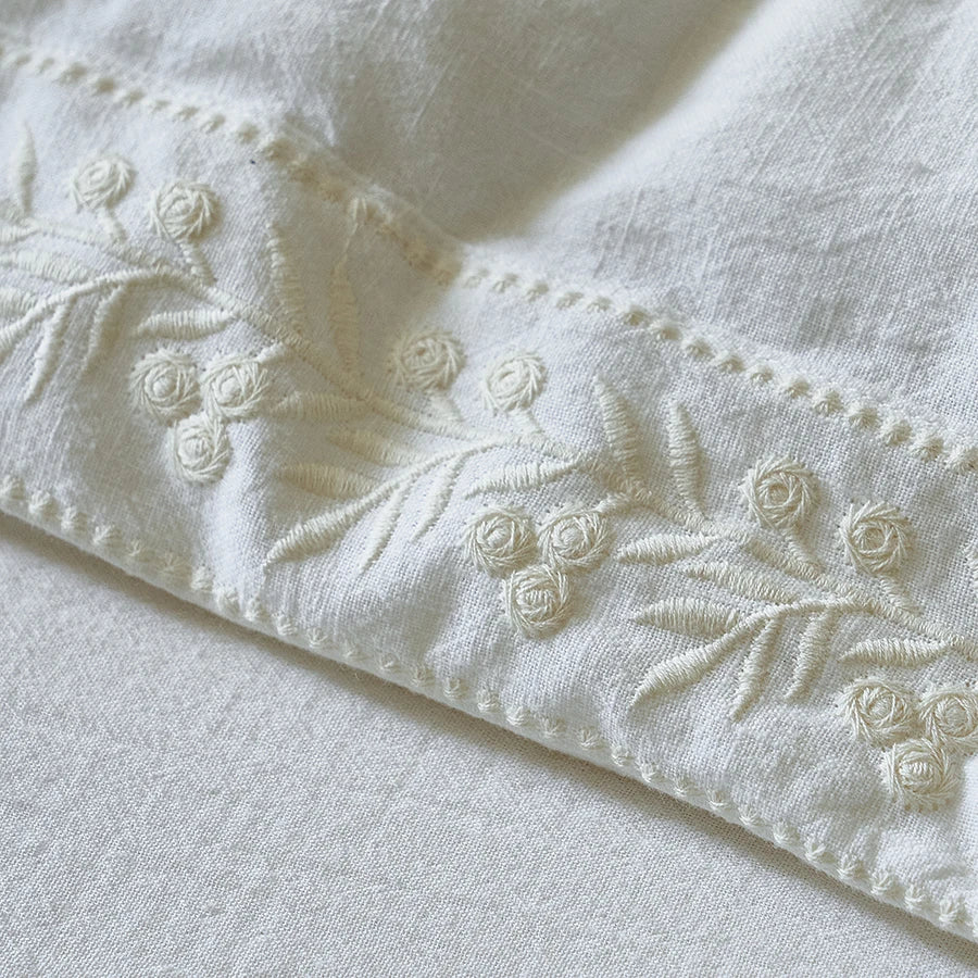 Close-up of white bedding set with floral embroidery
