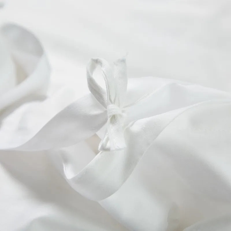 Close-up of white fabric with folds on a light gray background bedding set at the happy ladies.