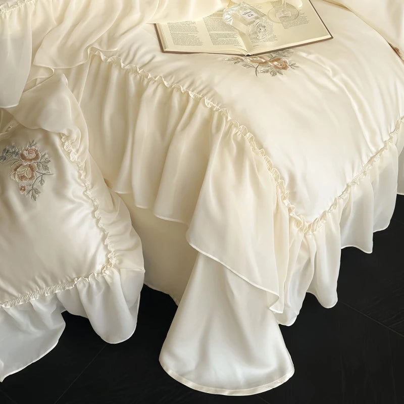 Cream-colored ruffled bedspread with floral embroidery on a dark surface