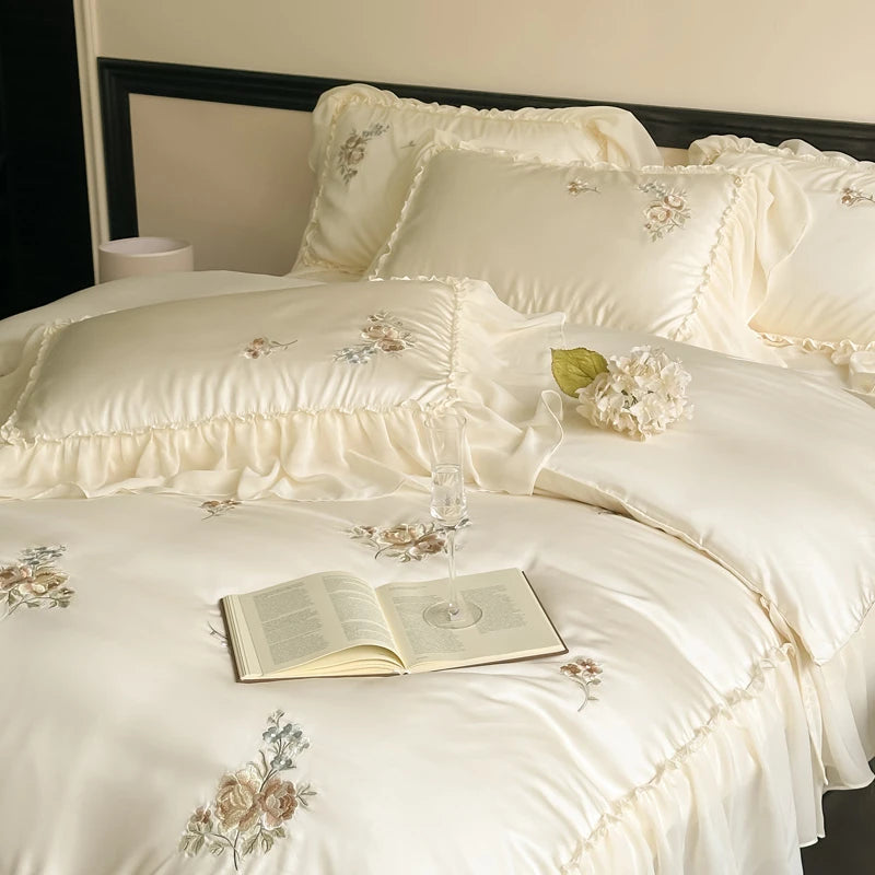Cream bedding set with floral embroidery on a bed.