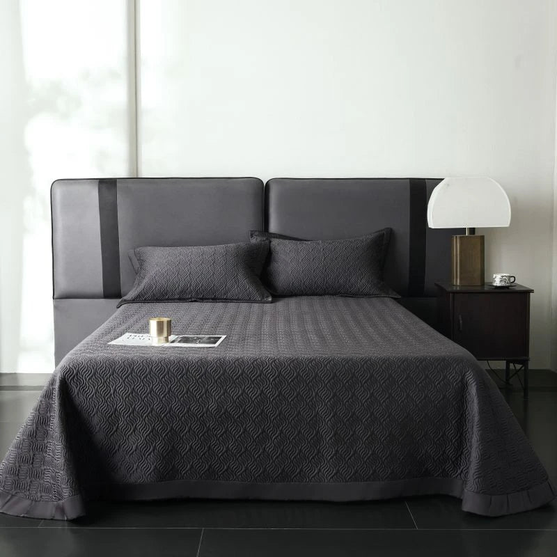 Dark Gray quilted bedspread on a bed in a minimalistic bedroom setting.