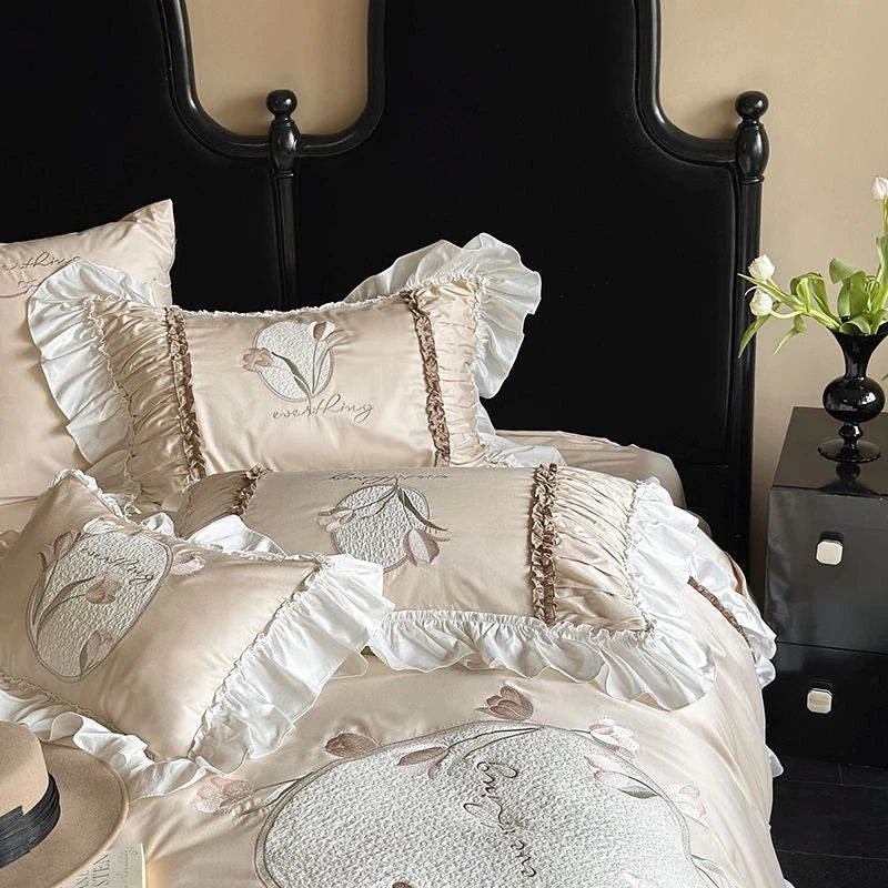 Decorative bedspread with floral embroidery on a bed with a black headboard.