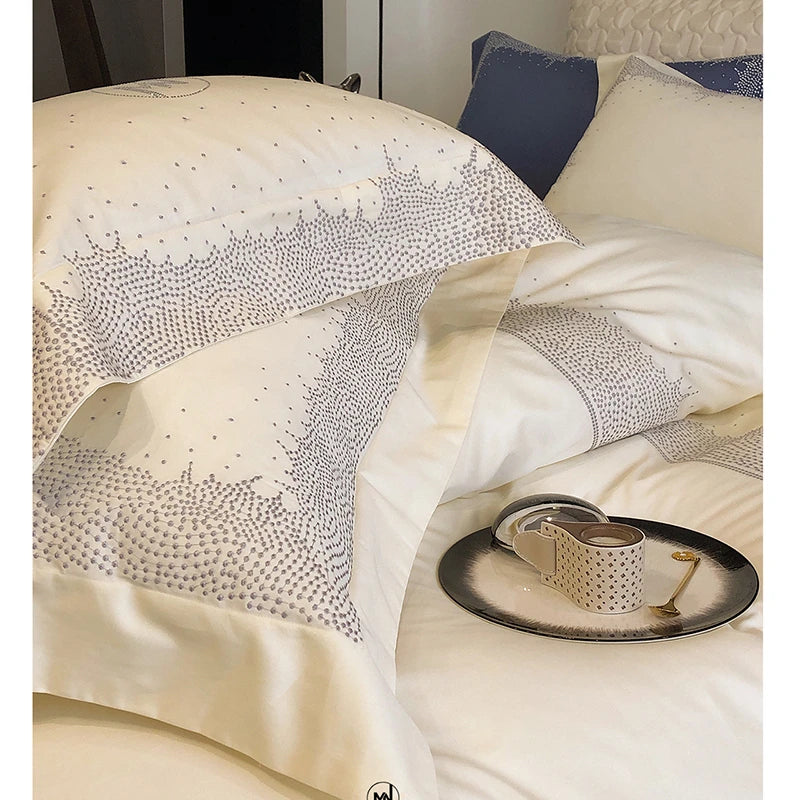 Decorative bedspread with intricate patterns on a bed with pillows and a tray.
