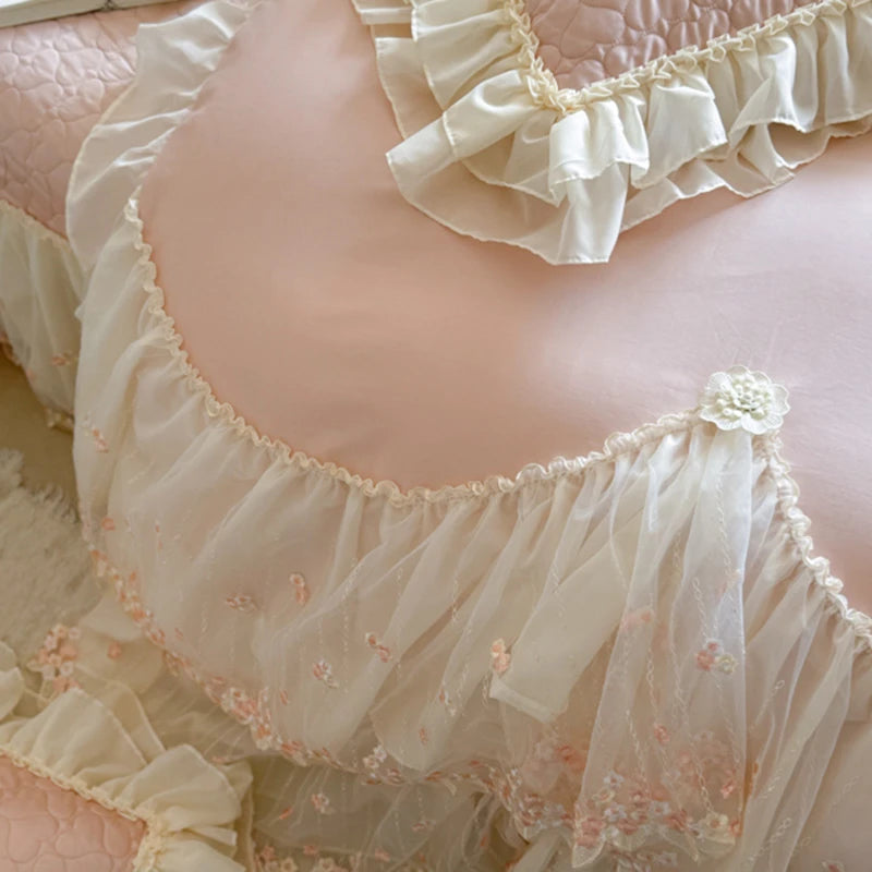 Delicate lace bed spread with ruffled edges and floral embroidery on a soft pink background