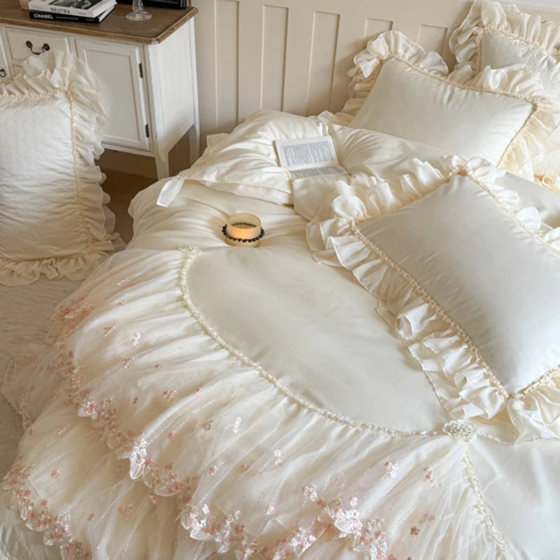 Delicate white bedding set with ruffles and floral embroidery in a bedroom setting.