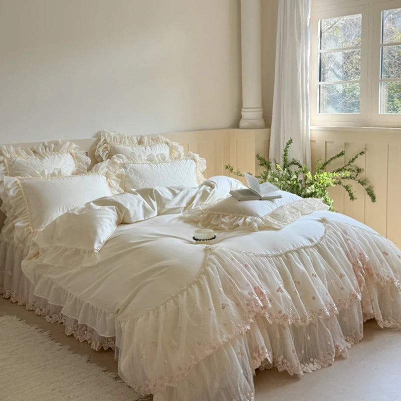 Delicate white ruffled bedding set on a bed in a softly lit room with a window and plant.